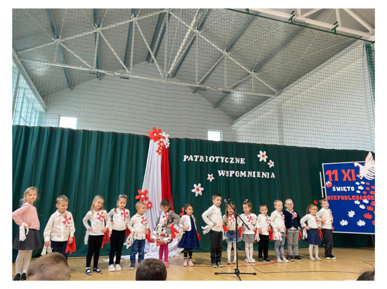 Zdjęcie grupy Motylków w galowych strojach. W tle napis Patriotyczne Wspomnienia i flaga Polski.